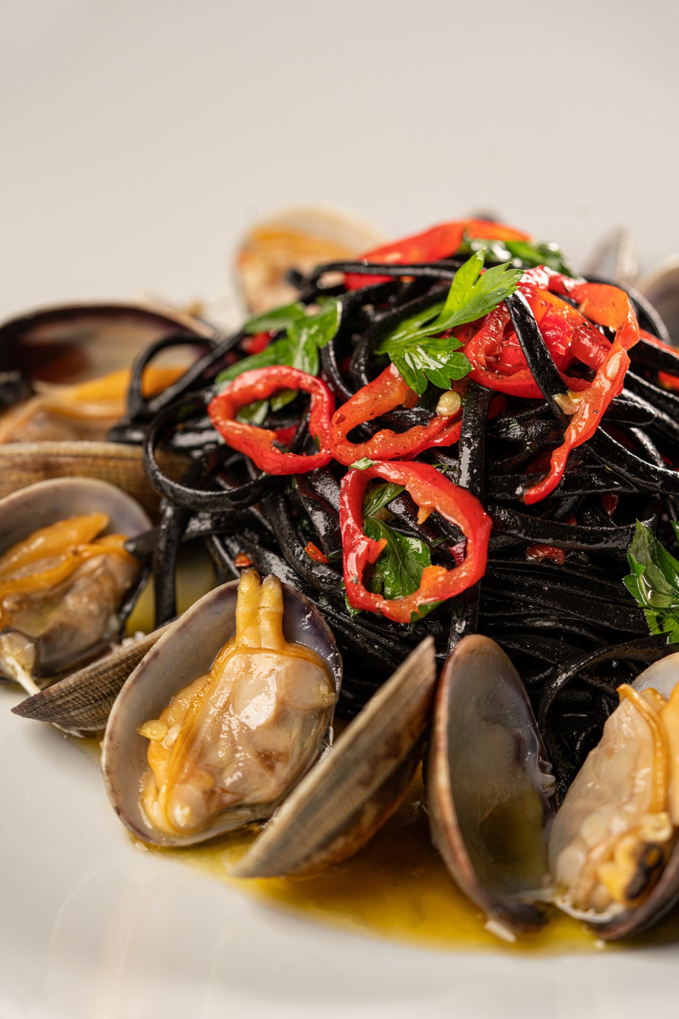 Close-up of squid ink pasta with chili, parsley and clams